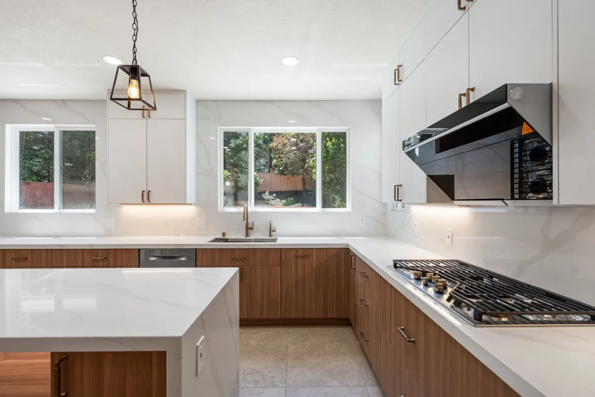 U-shaped kitchen with a gas cooktop under a black hood and windows along the counter