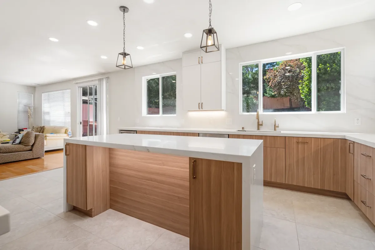 Island and walnut peninsula under a vaulted ceiling, open to the living room