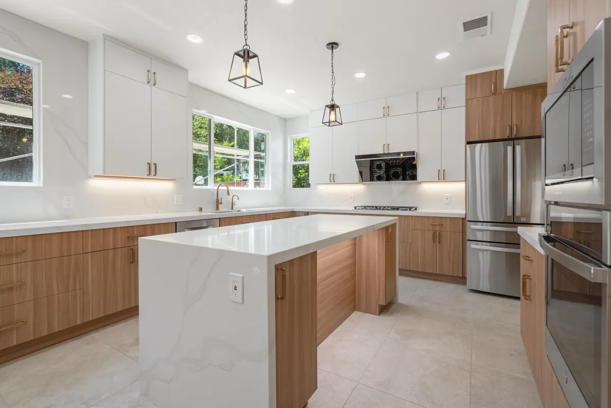 Wide kitchen view with the waterfall island, wall ovens and clerestory windows