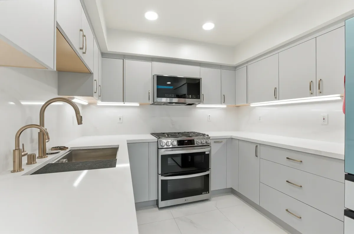 Sink and range along a quartz counter with under-cabinet lighting above