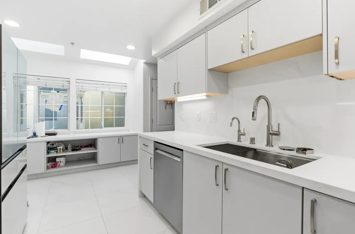 Kitchen under a skylight with a sink island, open shelving and a window wall