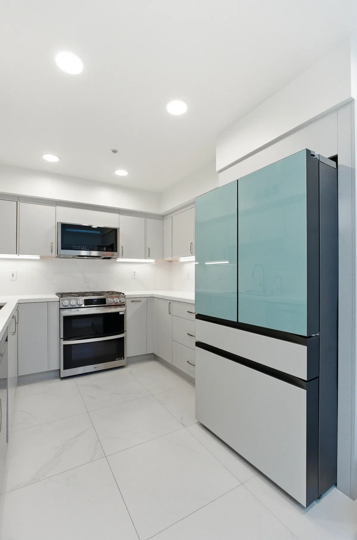 Full-height sea-green glass-panel refrigerator beside the grey cabinet run and range