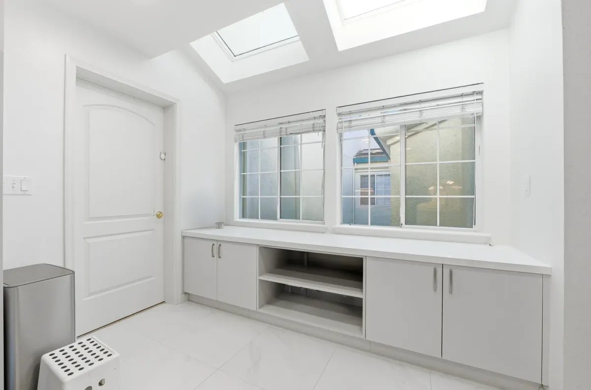 Built-in cabinet run and open shelf under a window, lit by a skylight