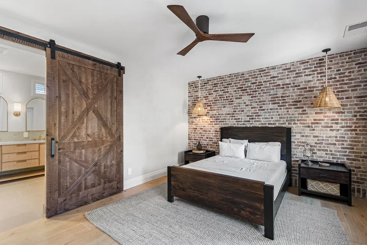 Bedroom suite with sliding barn door and brick accent wall