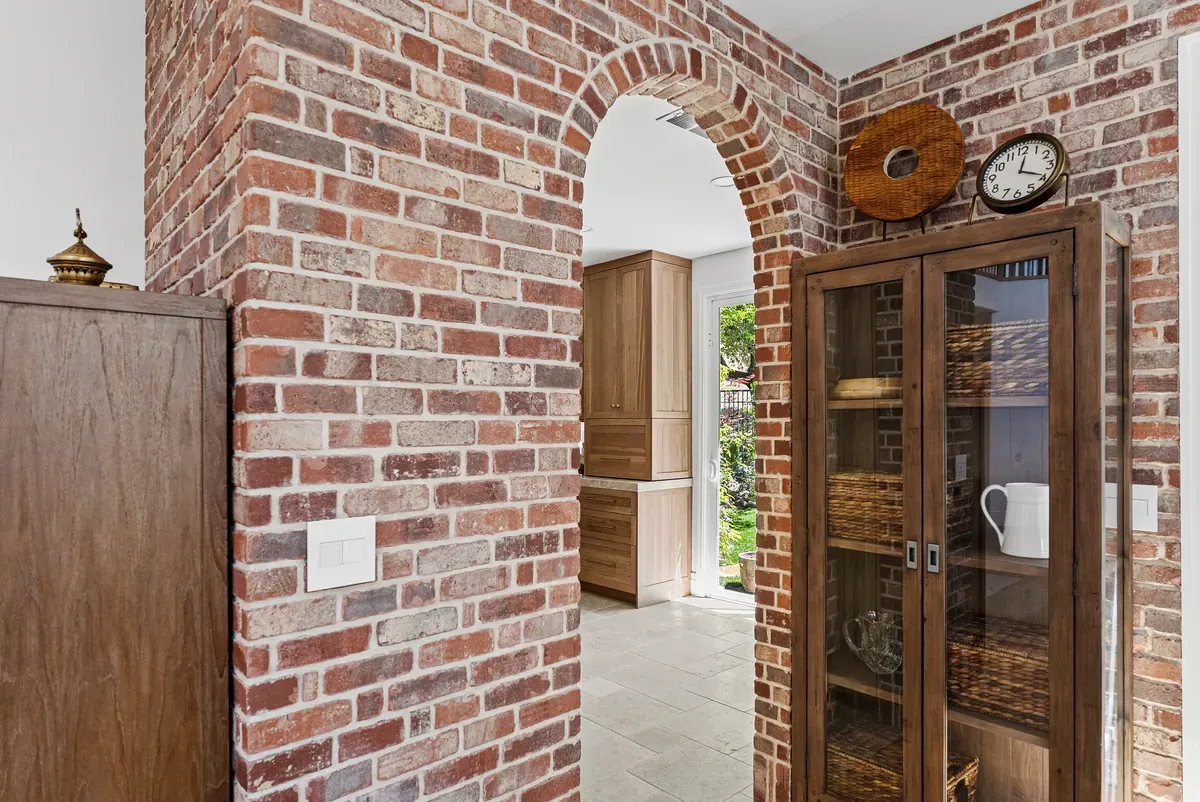 Exposed brick archway with antique display cabinet