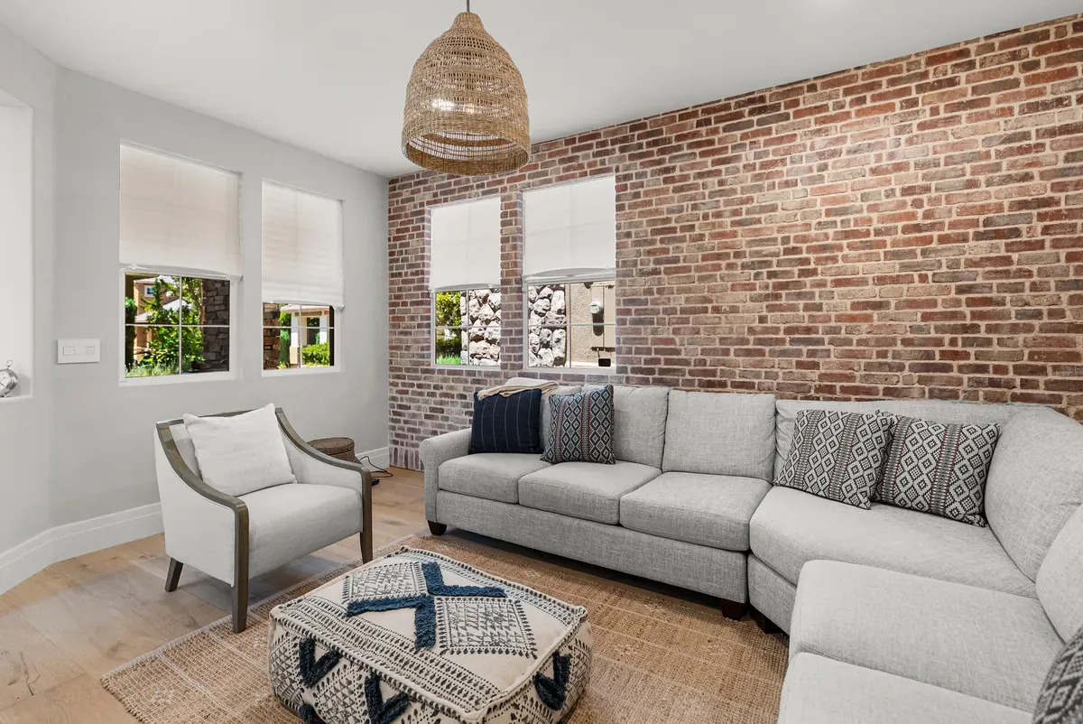 Living room with exposed brick wall, rattan pendant and sectional sofa
