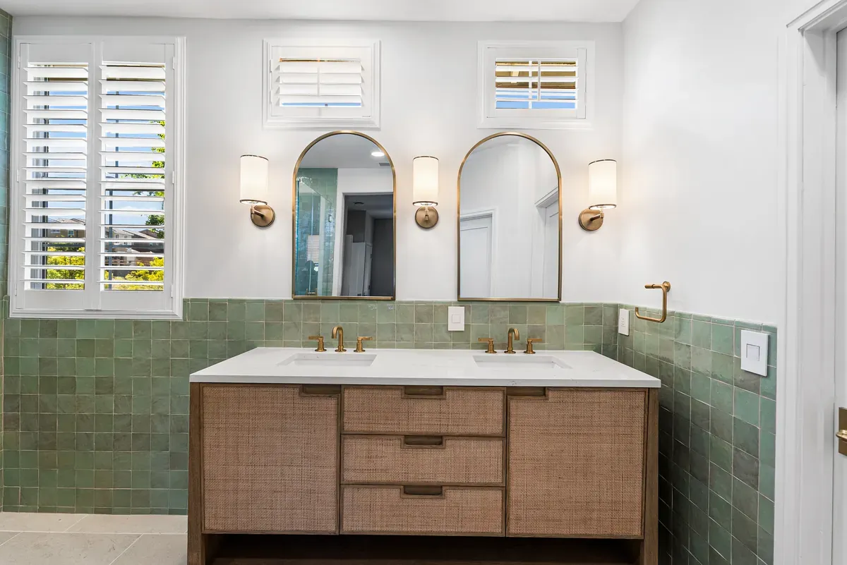 Primary bath double vanity with arched brass mirrors and green zellige tile