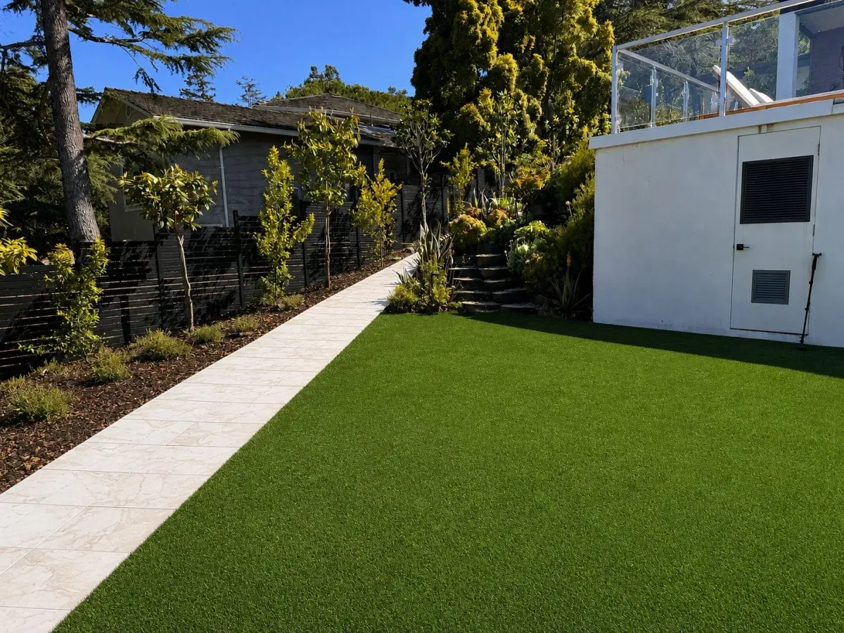 Paver walkway beside new turf and planting below a hillside home