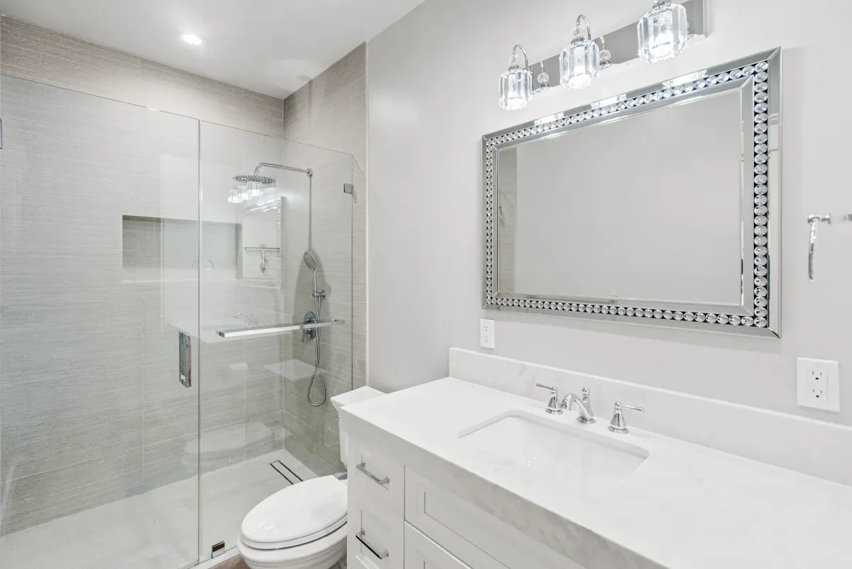 Bath with a glass shower, vanity and an ornate silver-framed mirror