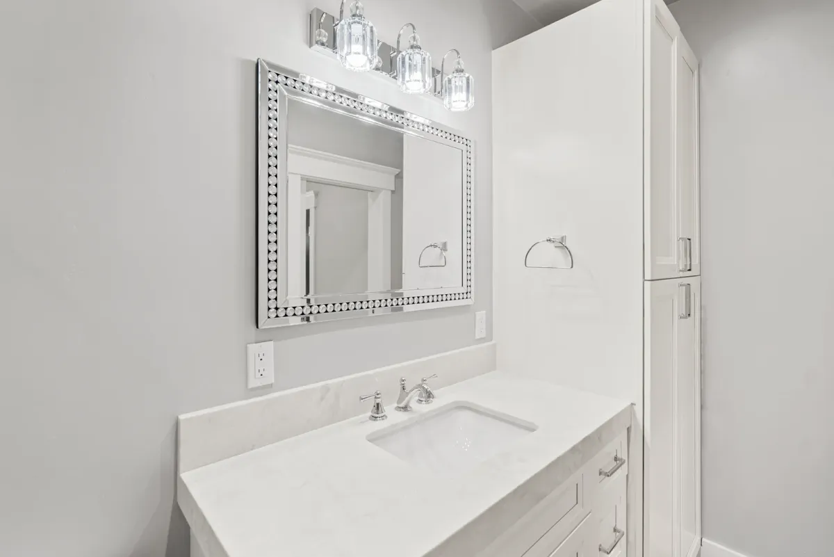 Bath vanity with a silver-framed mirror and glass sconces