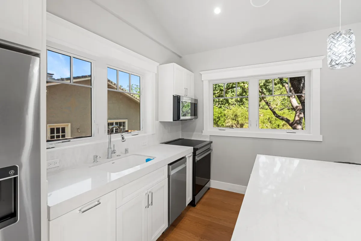 Kitchen counter with the sink, dishwasher and windows, island edge at right