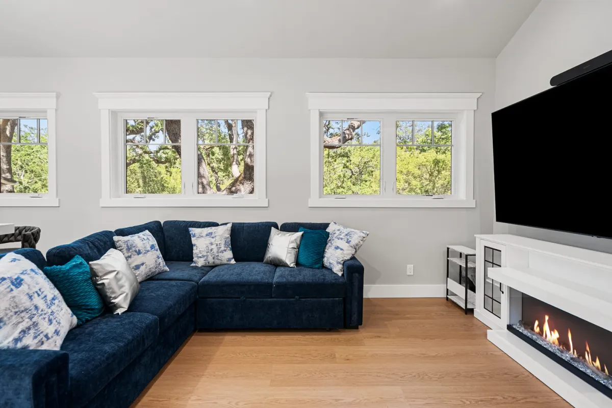 Navy sectional facing a linear fireplace and wall-mounted TV under clerestory windows