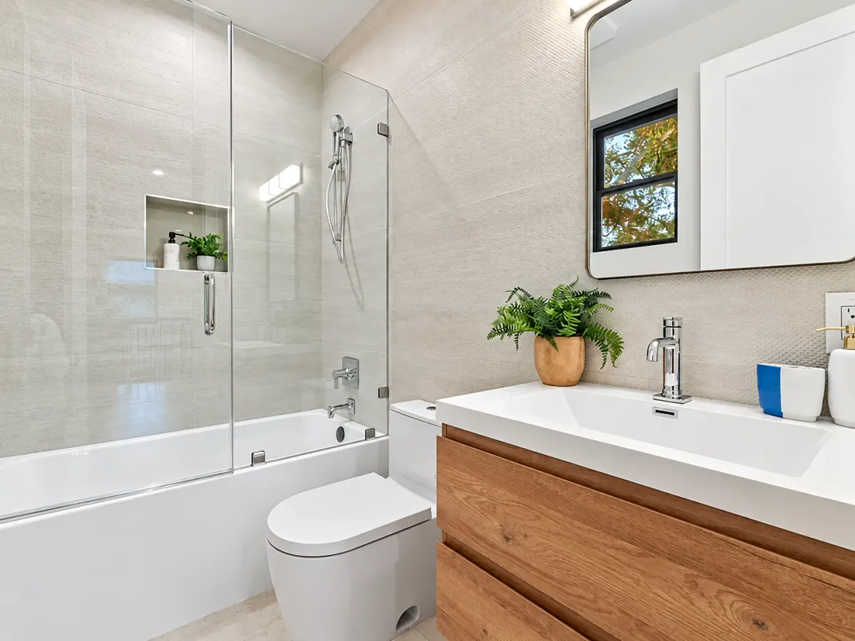 Guest bath with a glass-panel shower over the tub and a wall-hung oak vanity