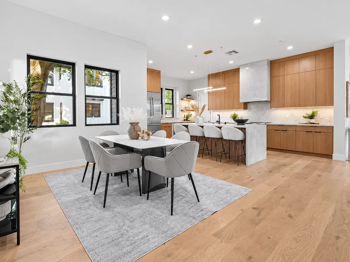 Dining table on a wool rug with black-framed windows and the kitchen beyond