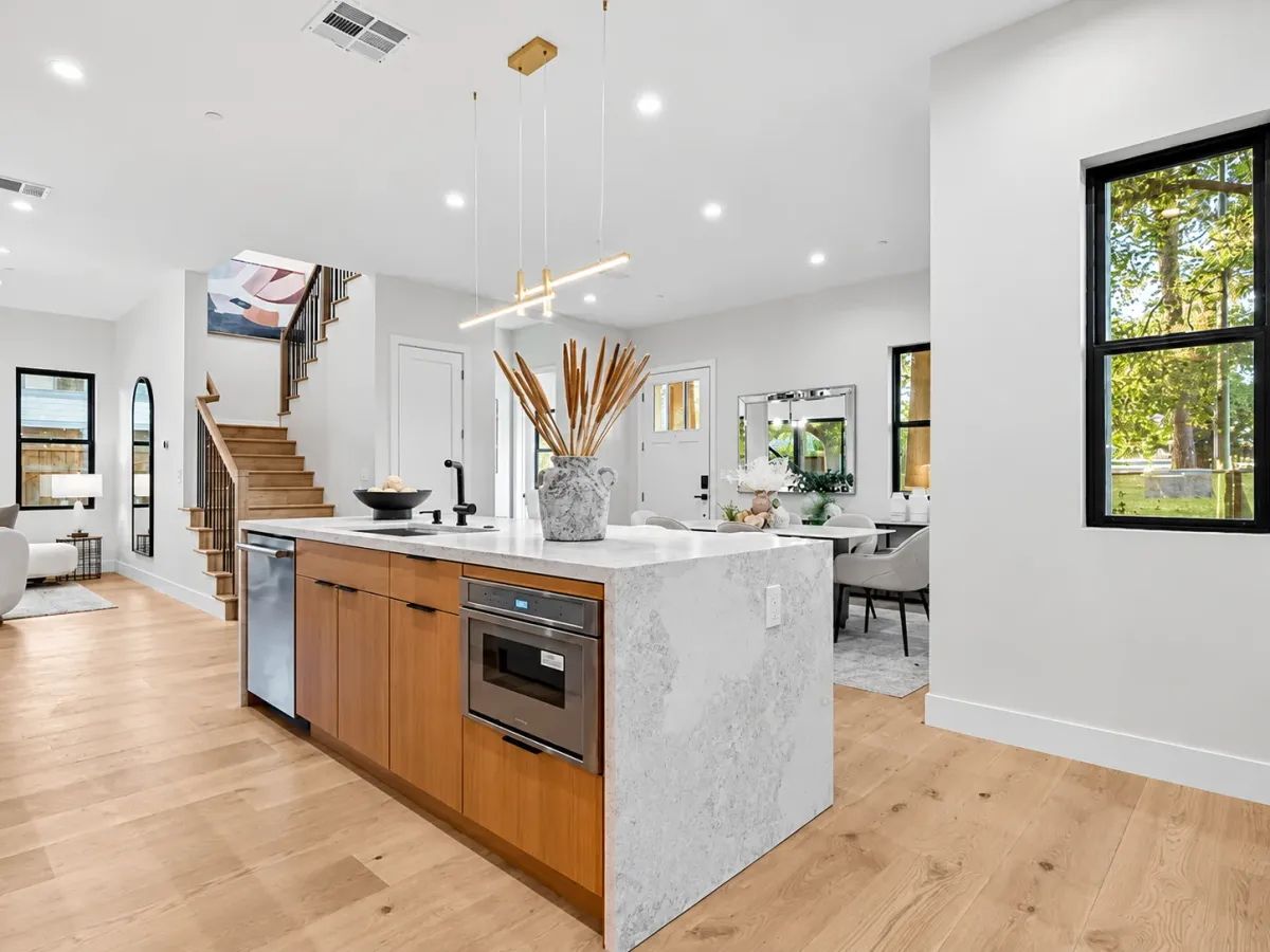 Kitchen island with a waterfall stone end and built-in oven, open to the staircase and living room