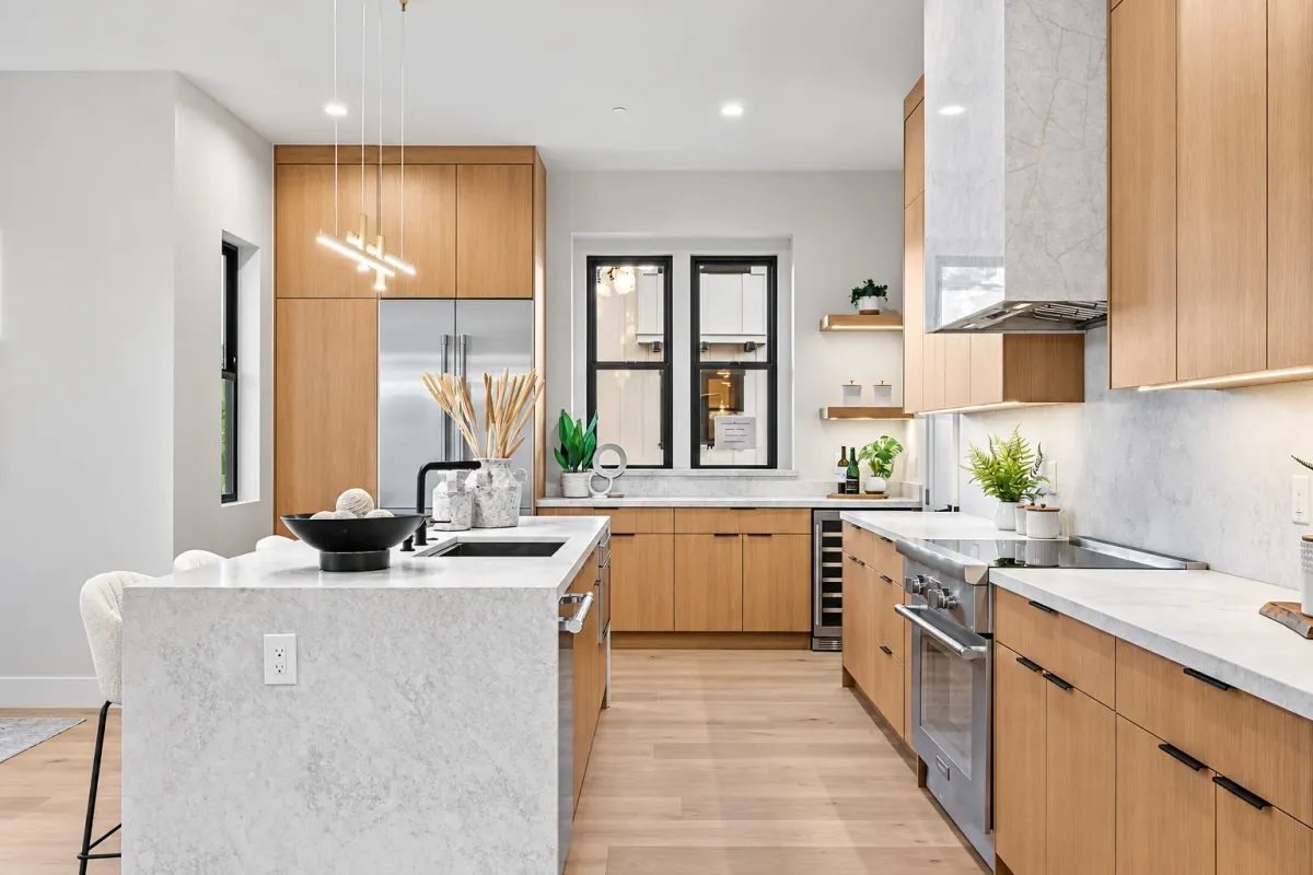 Kitchen range wall with a panelled hood, wine fridge and stone counters under oak cabinets