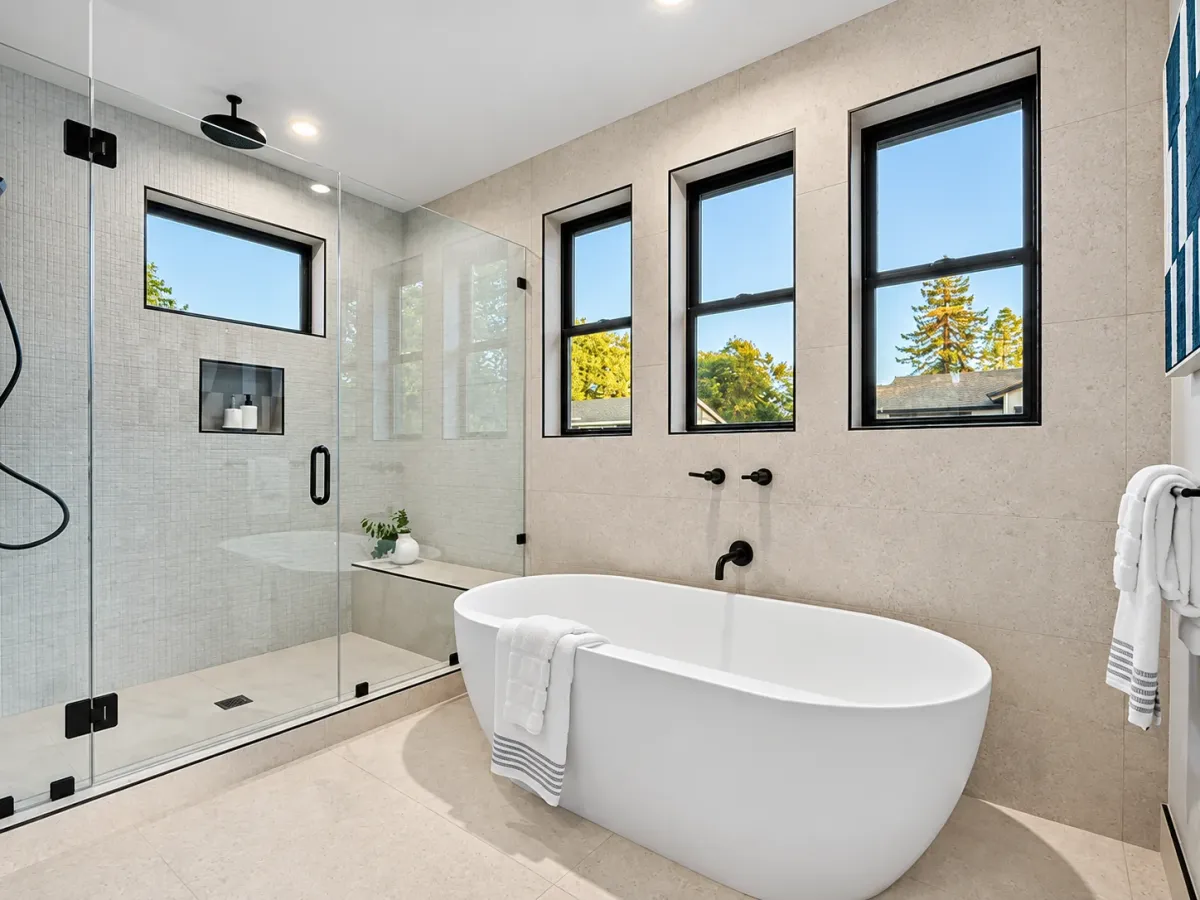 Primary bath with a freestanding tub, glass shower and black-framed clerestory windows, Mountain View complete home remodel