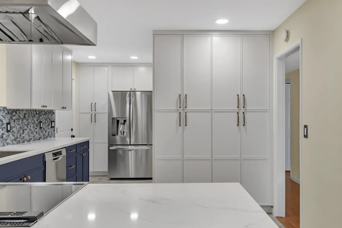 Island cooktop under a stainless island hood with a blue-grey mosaic backsplash behind