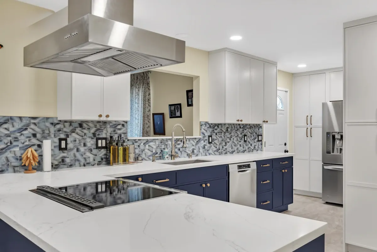 Navy base cabinets and white uppers with a dishwasher and brass pulls