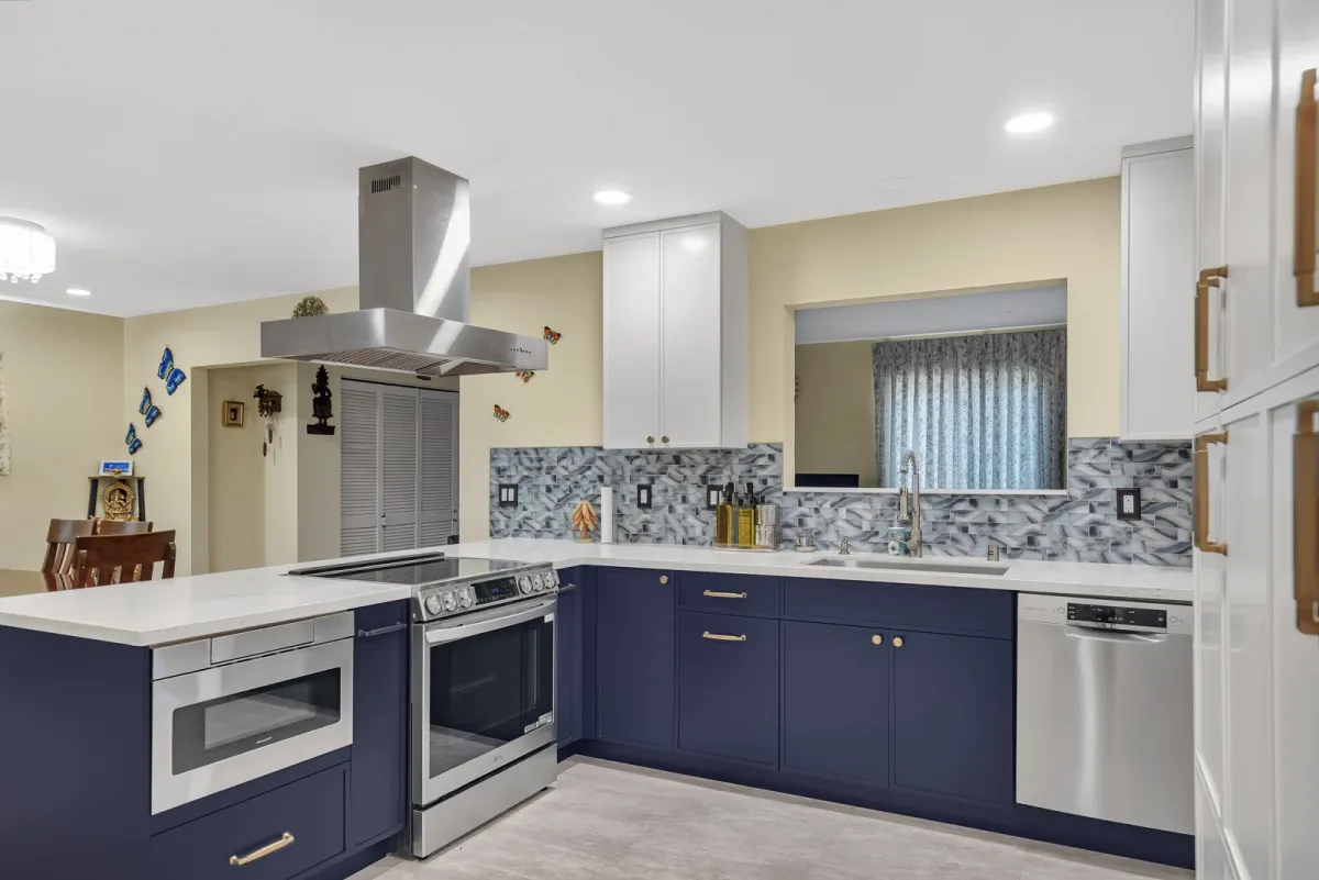Navy kitchen cabinets under white uppers with a stainless island hood and blue-grey mosaic backsplash, San Jose kitchen remodel