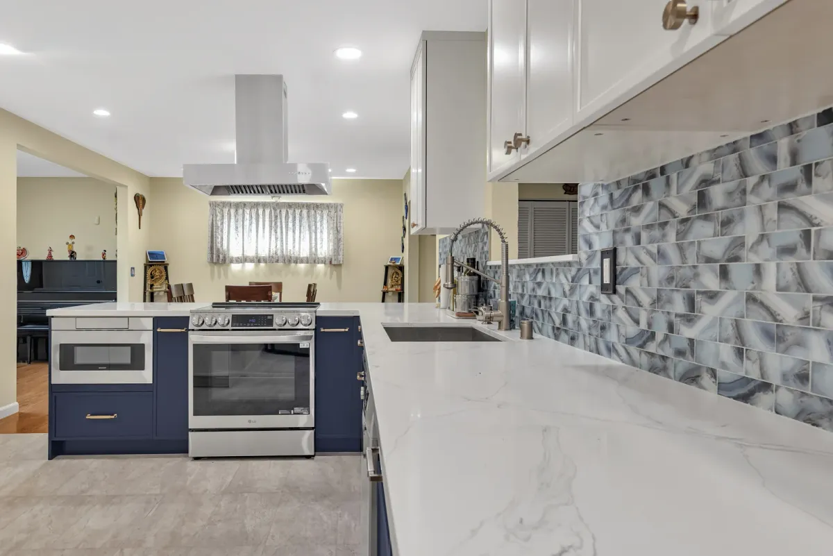 Navy L-shaped cabinet run with the range, microwave and mosaic tile