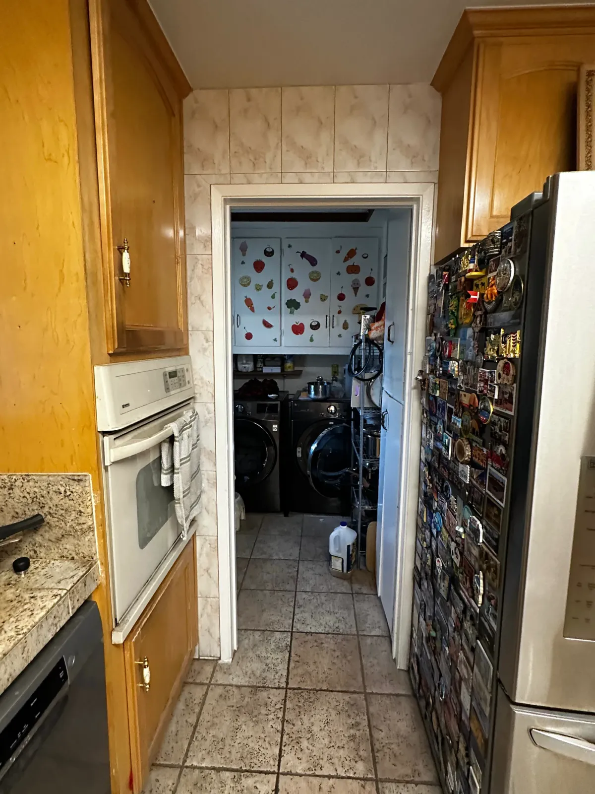 Before the remodel, a narrow oak run with wall ovens and a doorway through to the laundry