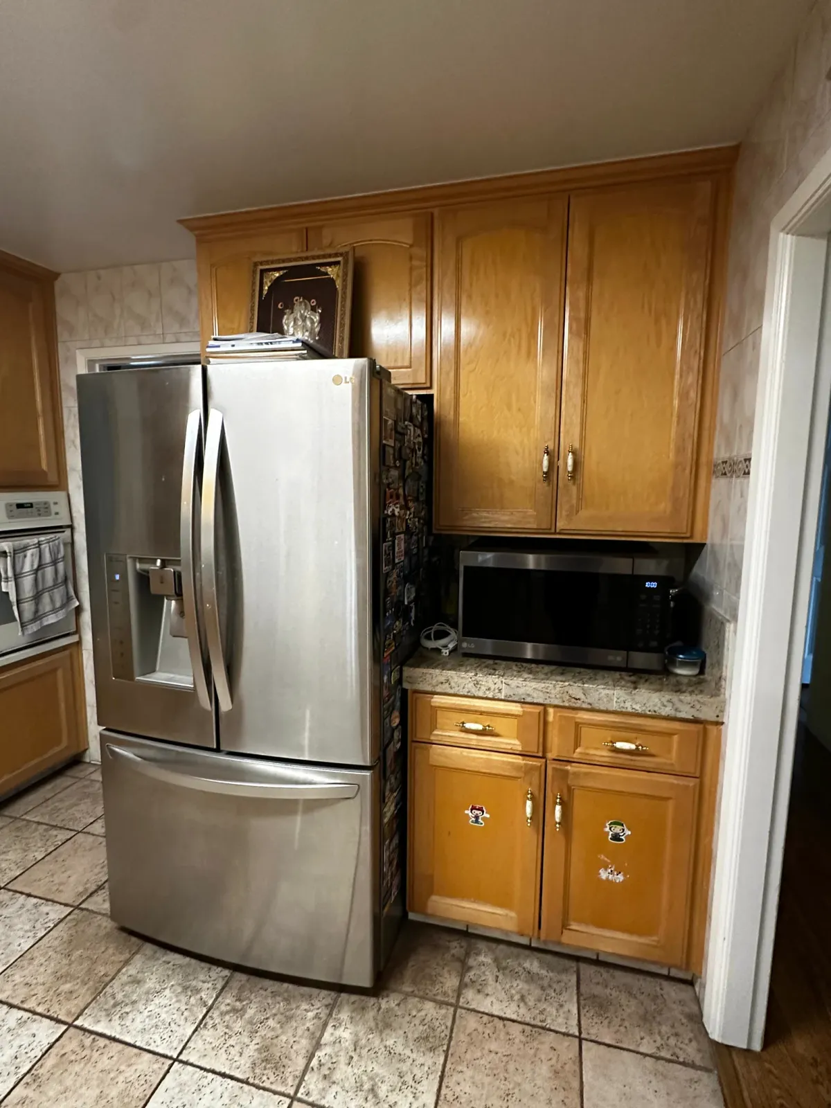 Before the remodel, oak cabinets and tile floor with a microwave over the counter