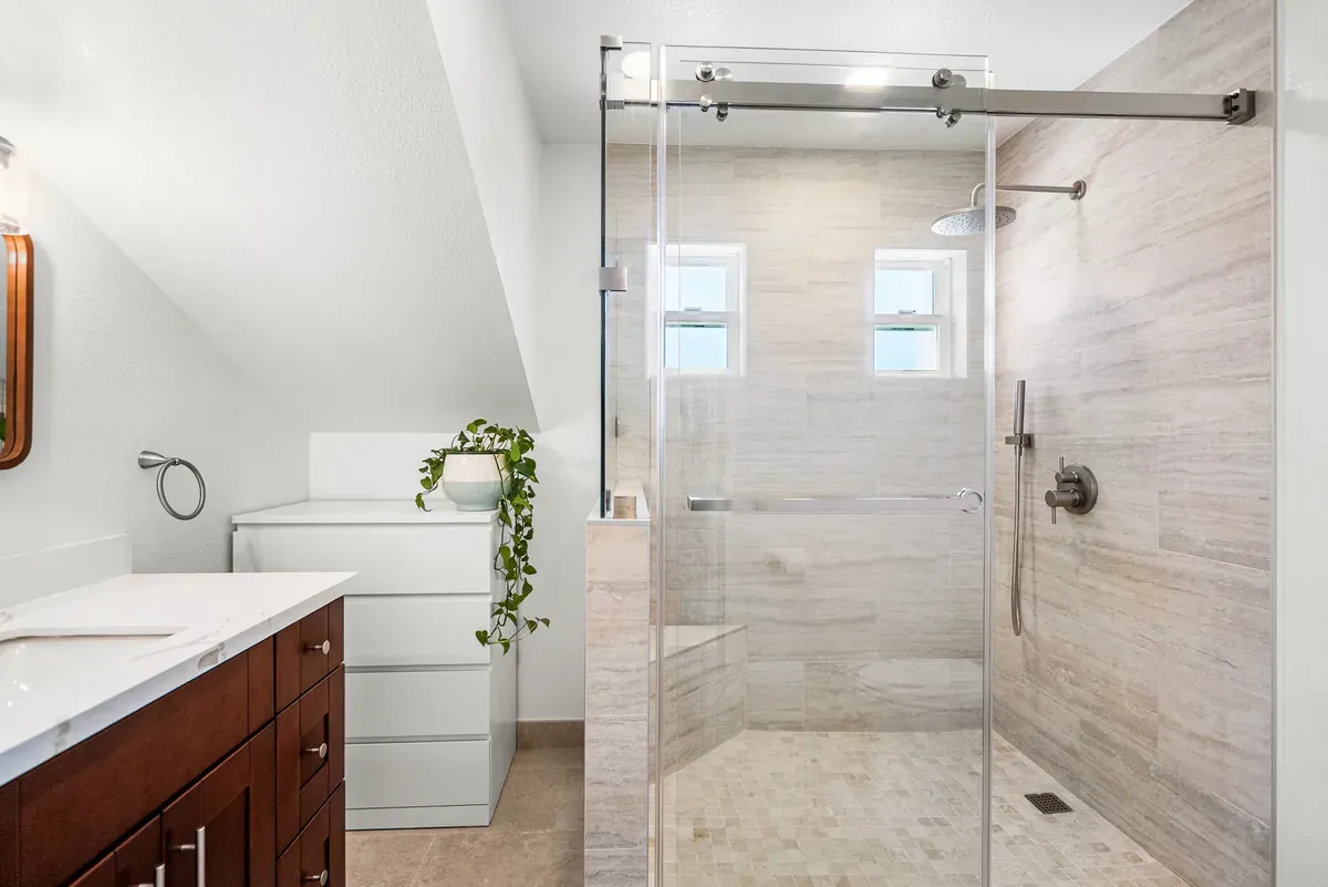 Bath suite with glass shower, white vanity and trailing plant