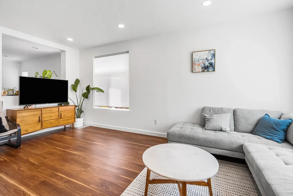 Living room with walnut floors, mid-century media console and leafy plants